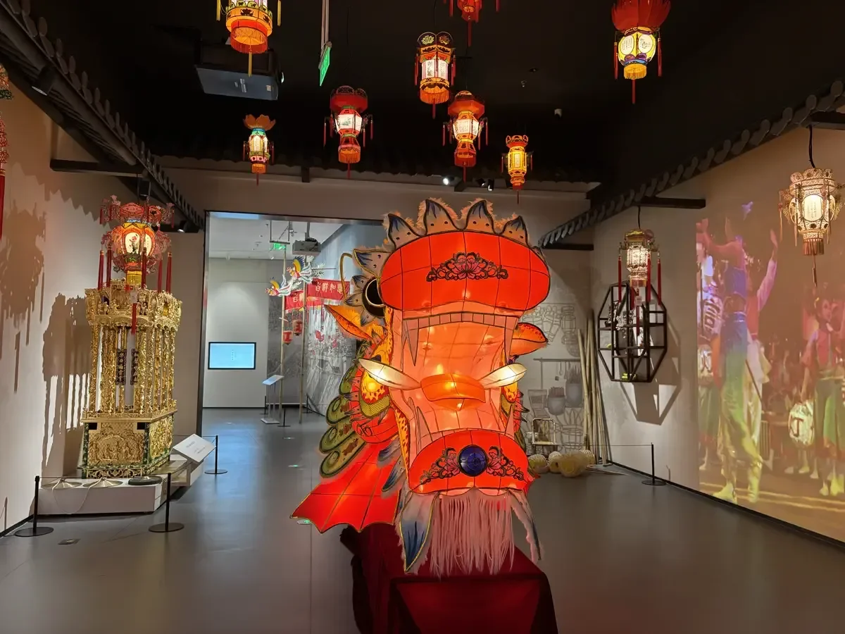 Exhibition gallery inside the Intangible Cultural Heritage Museum featuring a giant dragon head lantern and gold woodcarving shrine