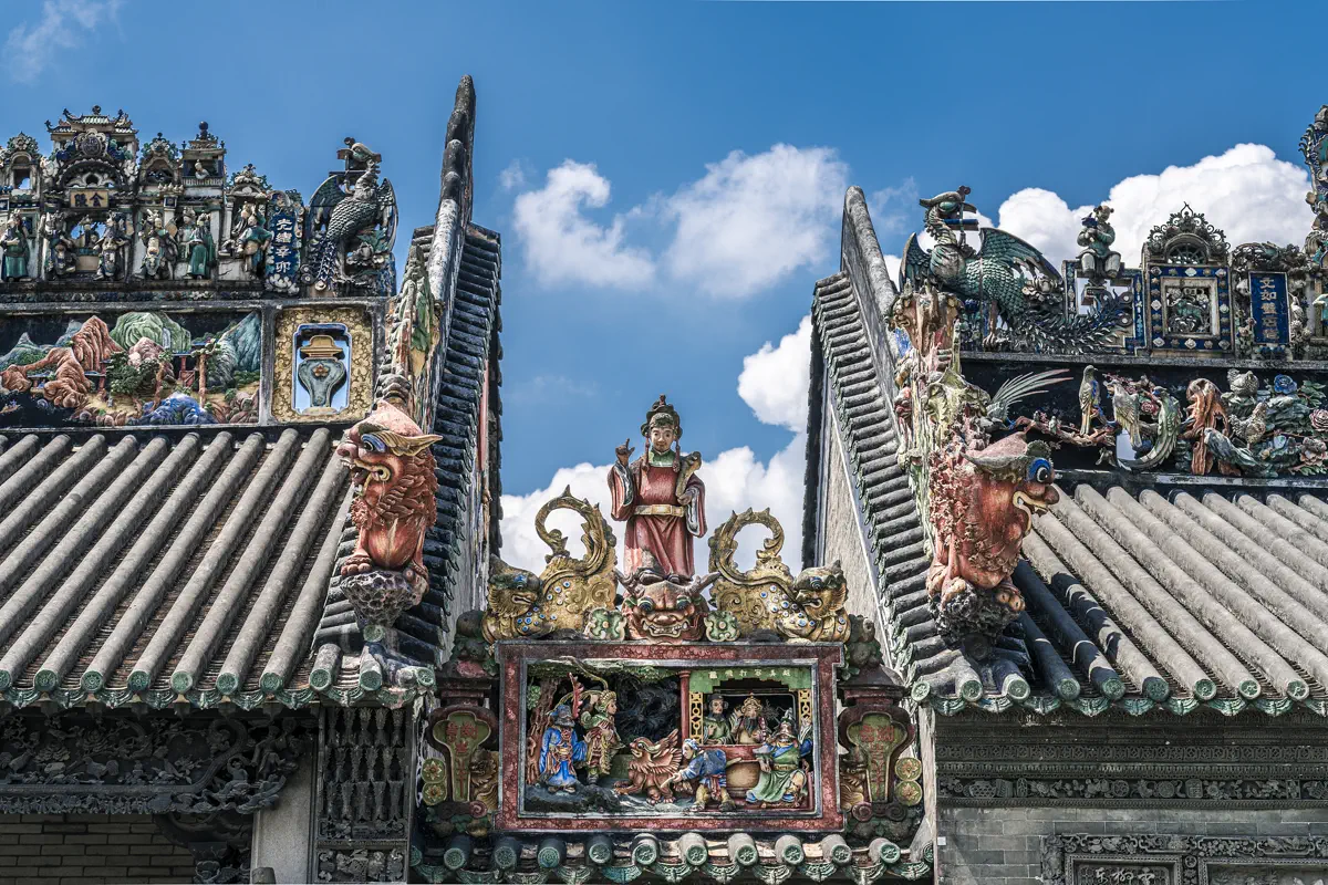 Close-up detail of Shiwan pottery figures, mythical dragon-carp aoyu, and colorful lime plaster sculptures on the roof ridge of Chen Clan Ancestral Hall