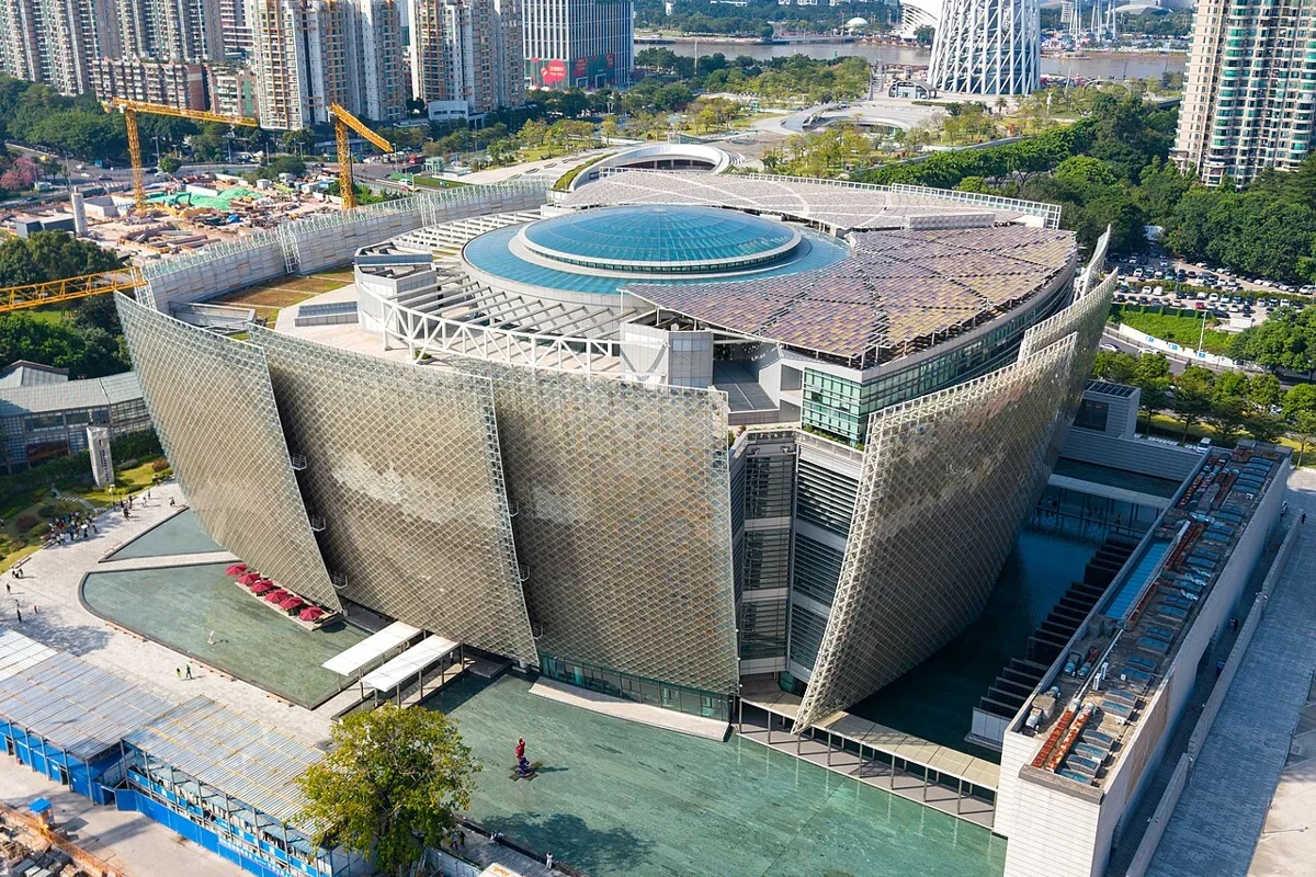 Aerial view capturing the five curved petal pavilions of the museum complex with Pearl River skyscrapers in the background