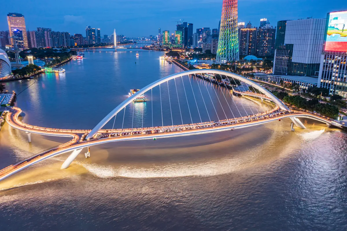 Nighttime aerial view of Haixin Bridge illuminated in golden light crossing the Pearl River with Canton Tower glowing in rainbow LED hues