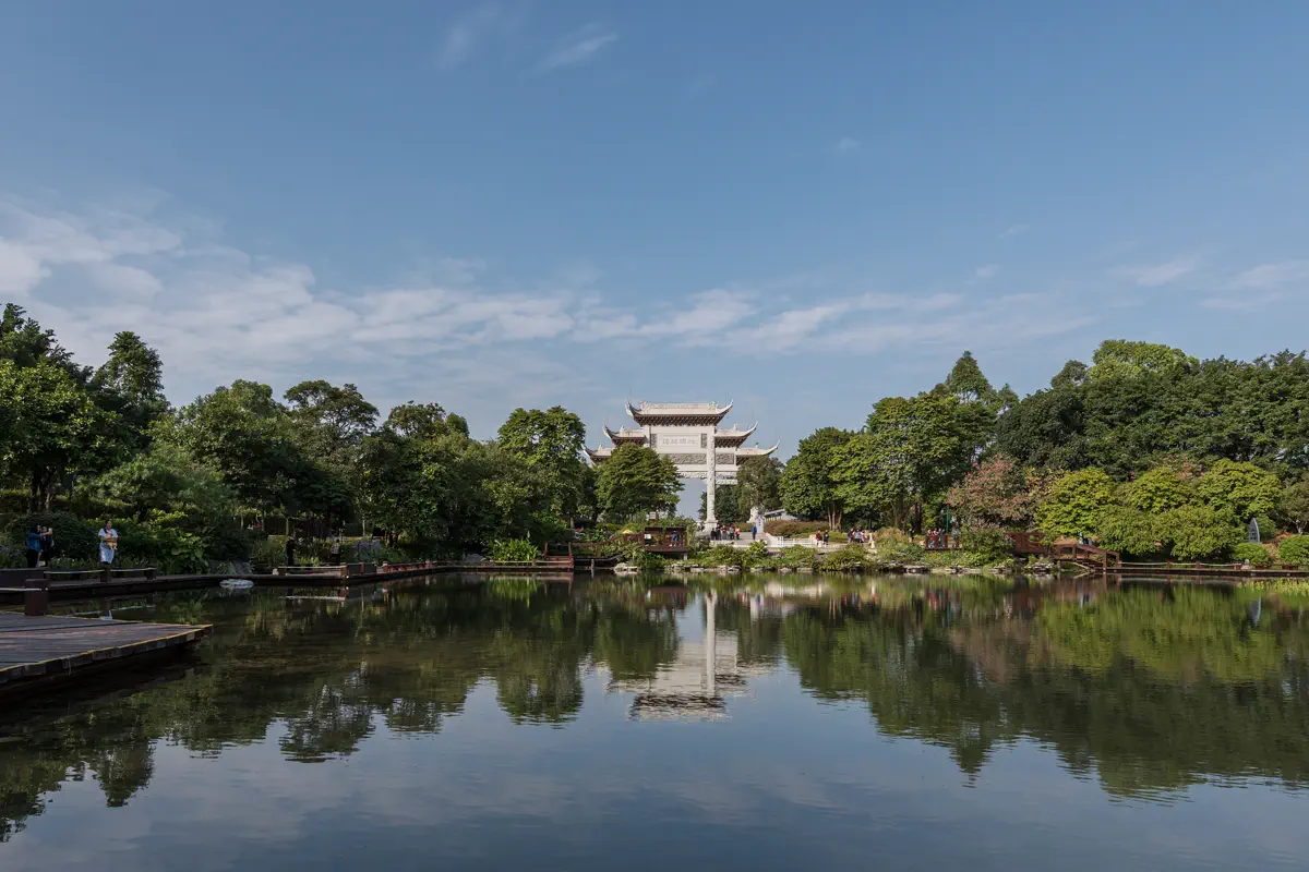 Traditional white stone ceremonial archway gate of Haizhu Wetland reflected across tranquil lake waters