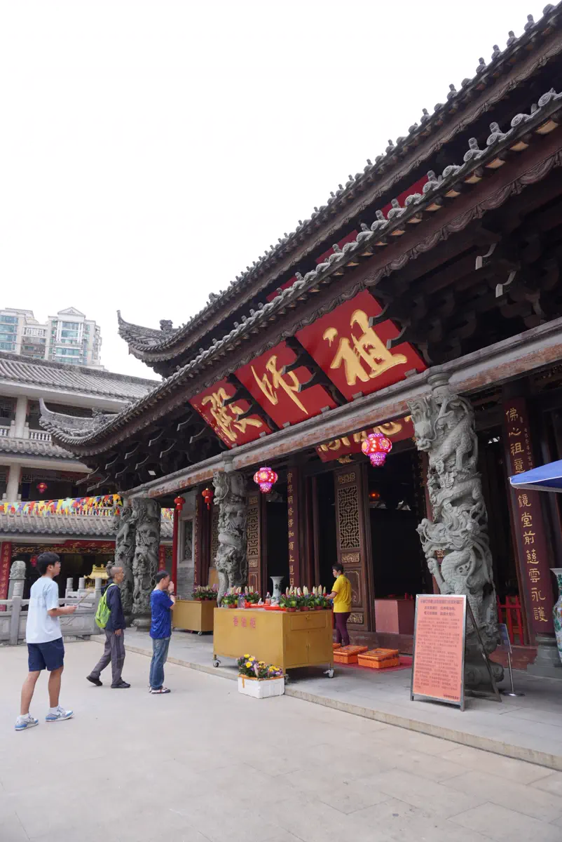 Worshipers burning incense in front of the Ancestor Hall at Hualin Temple flanked by stone carved dragon columns