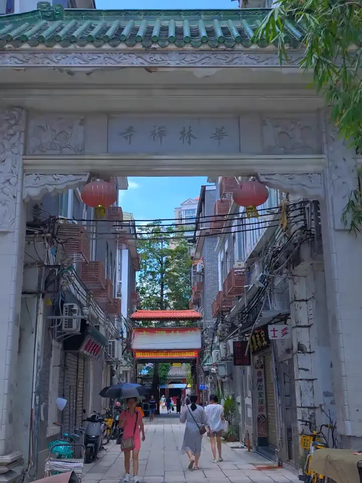 Traditional stone archway of Hualin Buddhist Temple framing a lively shopping street in Guangzhou's old Xiguan district