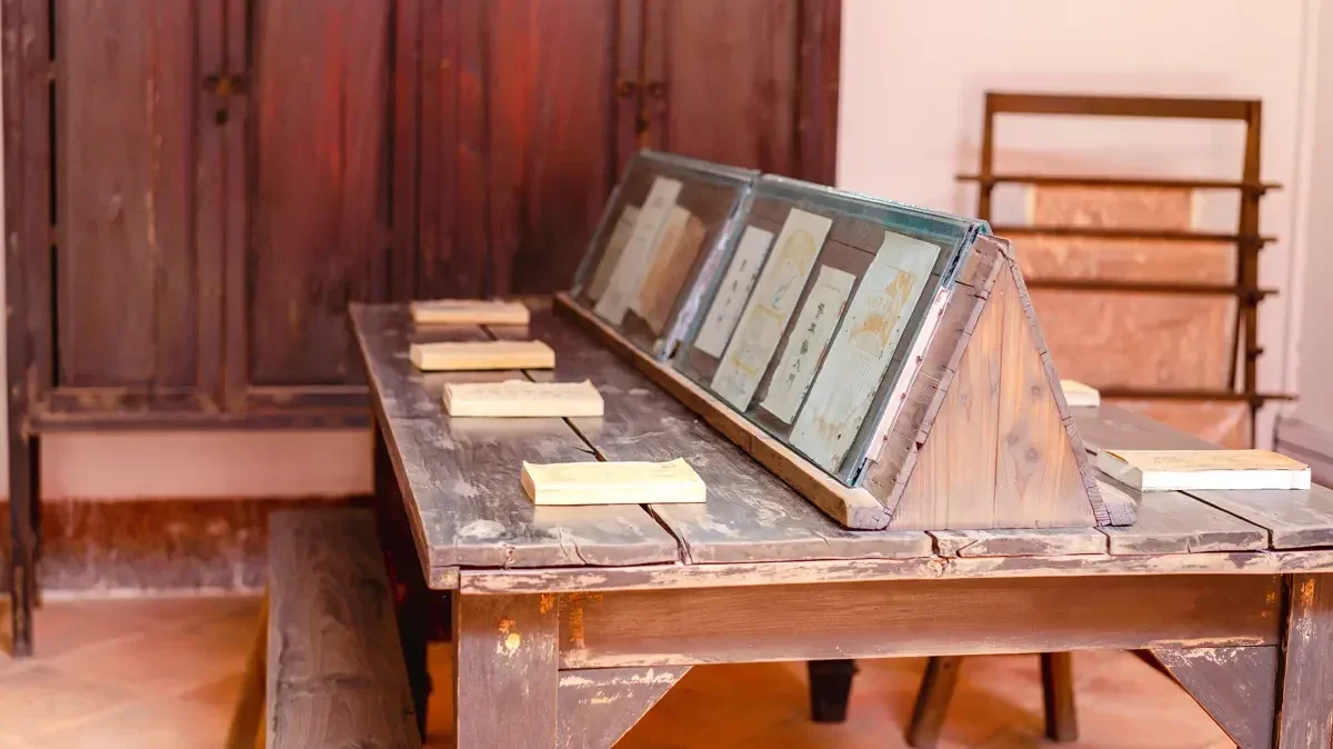Historic wooden reading room with angled display bookstands and printed revolutionary journals from the Sixth Peasant Movement Institute