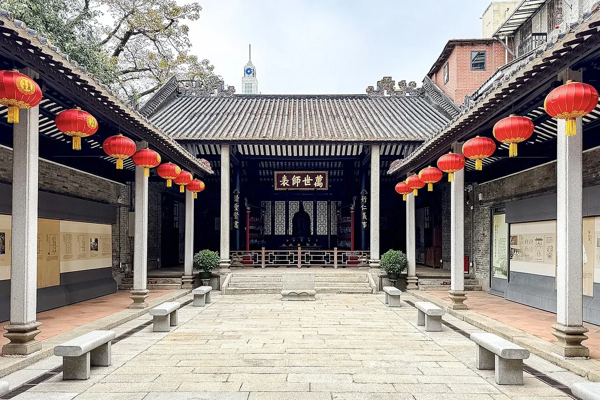 Central courtyard of Minglun Hall flanked by covered corridors with hanging red lanterns and the imperial Wan Shi Shi Biao banner
