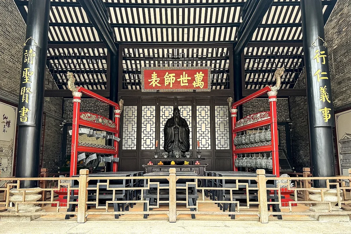 Bronze statue of Confucius in teaching gesture flanked by bianzhong bronze chimes and bianqing ritual stone chimes inside Minglun Hall