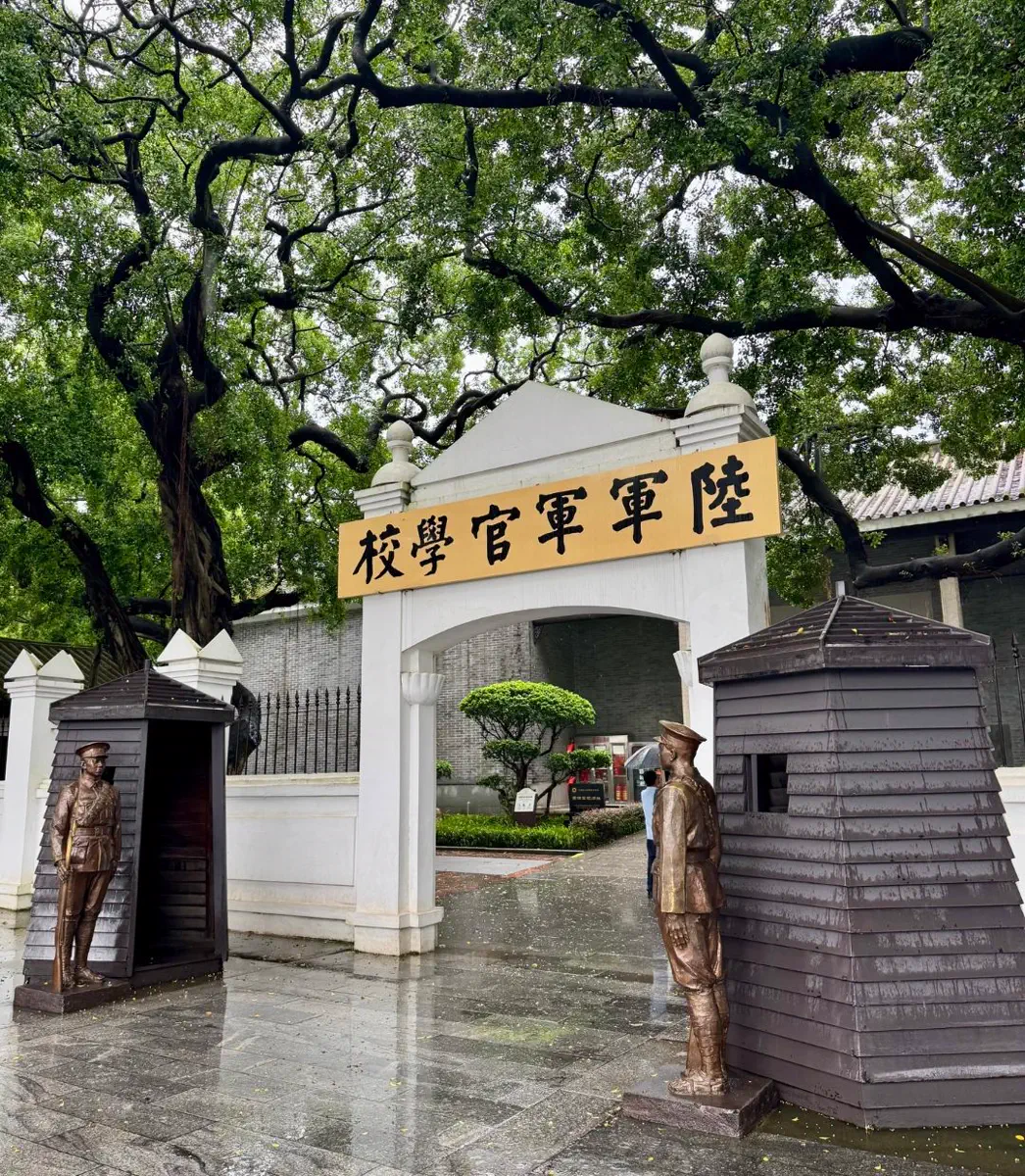 Close-up view of the entrance gate of Whampoa Military Academy flanked by bronze statues of standing cadet sentries